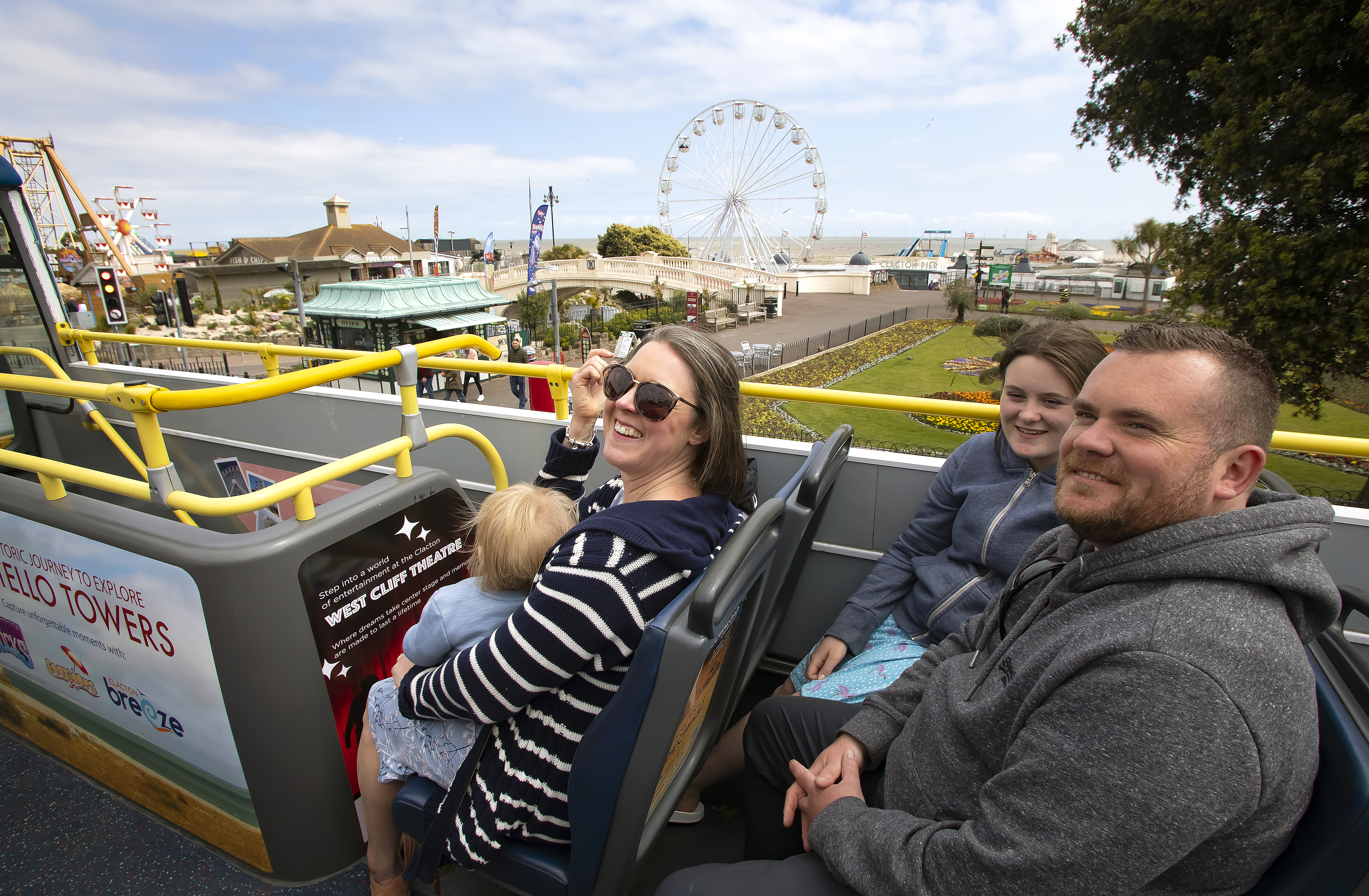 A Family on the top of an open top bus in Clacton over looking the Clacton Pier
